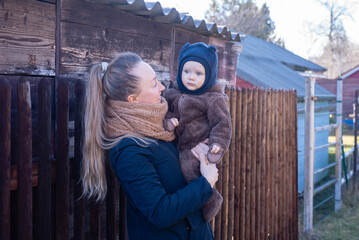 Woman holding baby in her hands against wooden wall. mother and son.