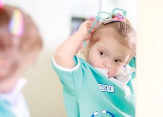 Portrait of a girl with Down syndrome. A girl in a doctor's playsuit. The child plays role-playing...