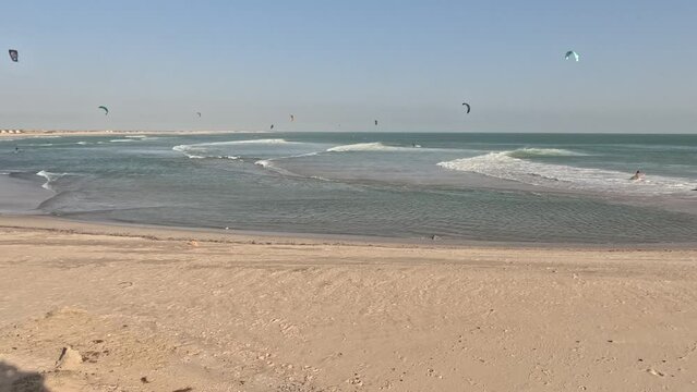 Timelapse is located on a beach in the sea of Dakhla gulf, Morocco. Where tourists practice kite surfing, wind surf, Kite board, skimboard, wing foil, and wakeboard, people enjoy water sports in ocean