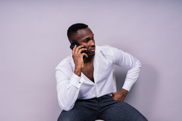 Handsome excited young african business man with mobile phone isolated over gray background