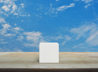 White block cubes on wooden table over blue sky with white clouds
