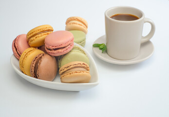 colorful macaroons on white tray with coffee cup and mint leaves isolated on white background and copy space