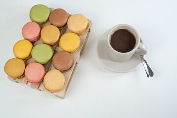 top view of colorful macaroons on a small wooden pallet and coffee cup isolated on white background and copy space