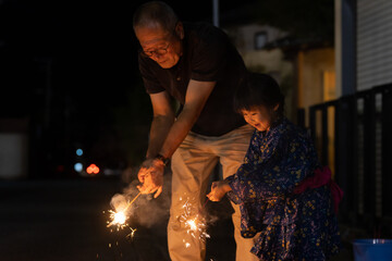 夏休みに帰省しておじいちゃんと花火をする子供