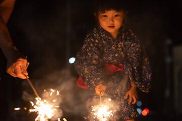 夏休みに帰省しておじいちゃんと花火をする子供