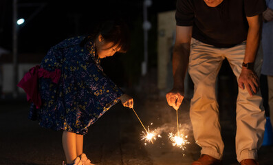 夏休みに帰省しておじいちゃんと花火をする子供