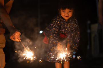 夏休みに帰省しておじいちゃんと花火をする子供