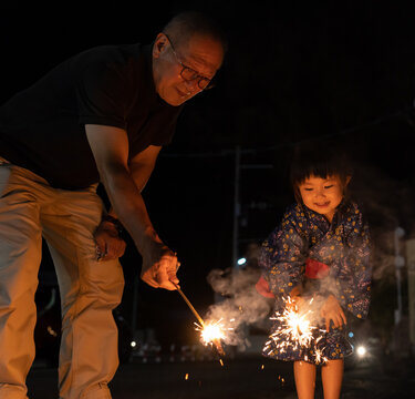 夏休みに帰省しておじいちゃんと花火をする子供