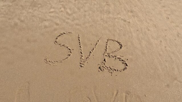 Silicon Valley Bank "SVB" logo is written on the beach sand and erased with a wave, a concept video of the bank crisis.