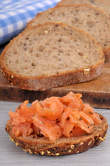 Toast avec des rillettes de truite en gros plan avec des tartines de pain aux graines au second plan