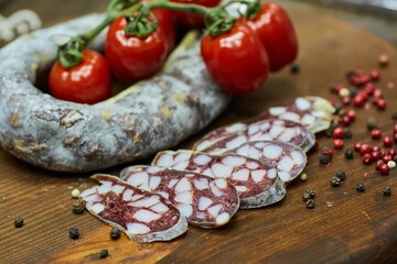 Dried or smoked sausage on a wooden table surrounded by spices and products. Meat production.