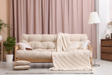 Comfortable sofa, cushions and blanket in cozy room. Interior design