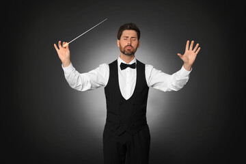 Professional conductor with baton on black background