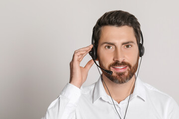 Hotline operator with headset on light grey background, space for text