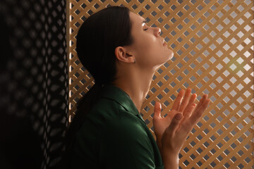 Woman praying to God during confession in booth