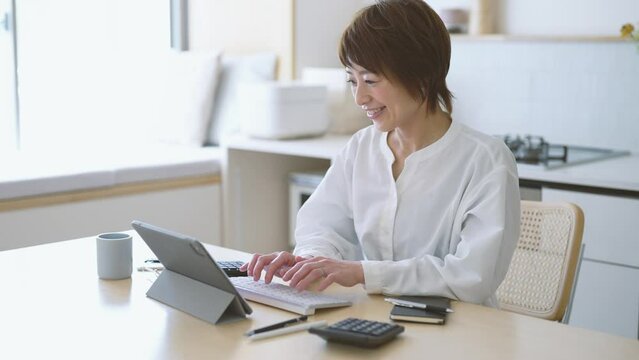自宅のダイニングキッチンで仕事をする女性
