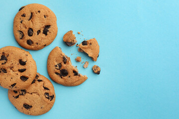 Many delicious chocolate chip cookies on light blue background, flat lay. Space for text