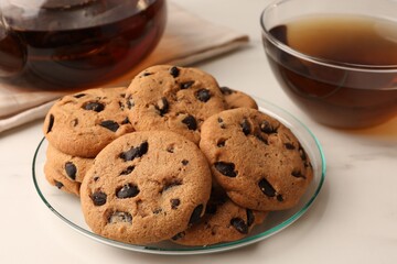 Delicious chocolate chip cookies and tea on white marble table, closeup