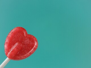 Concepto de amor Postal para enamorados Piruleta roja en forma de corazón sobre fondo Verde con...