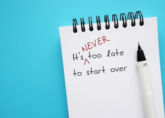 Notebook on copy space blue background with handwriting - It's never too late to start over - means to get out of a rut in career path, relationship or unhealthy habit, embrace new beginnings