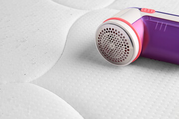 Fabric shaver on mattress with lint, closeup. Space for text