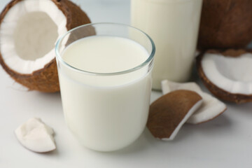Glass of delicious vegan milk and coconuts on white table, closeup