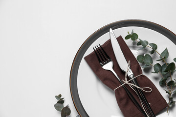 Stylish setting with cutlery and eucalyptus leaves on white background, top view. Space for text