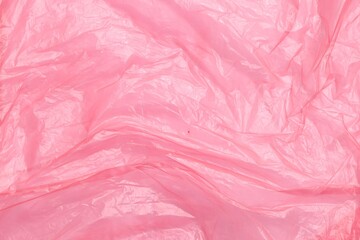 Crumpled pink plastic bag as background, top view
