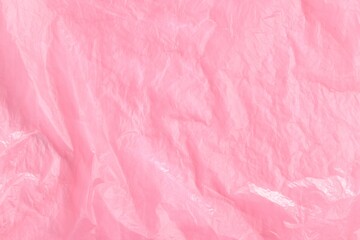 Fototapeta premium Crumpled pink plastic bag as background, top view