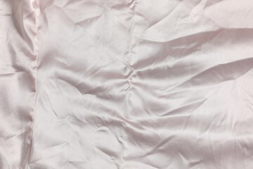 Crumpled light pink fabric as background, top view