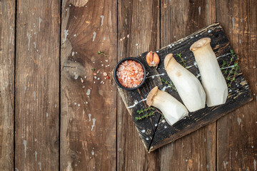 King oyster mushroom Pleurotus eryngii on a wooden background, banner, menu, recipe place for text,...