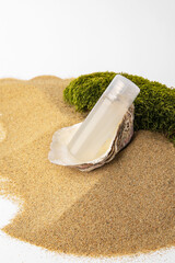 Bottle of serum and moss on sand against white background. Cosmetic product