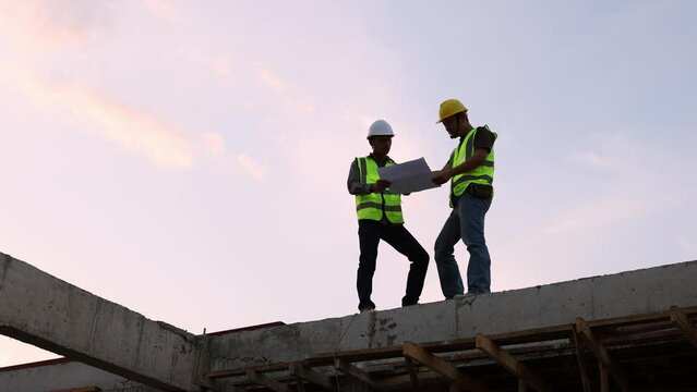 Construction engineers discussing project at construction site, Building construction collaboration concept, Video 4k slow motion.