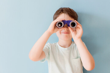 Child with binoculars on blue background