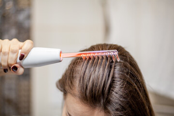 Naklejka premium Woman uses darsonval for massage head's skin. Receiving electric darsonval facial massage procedure. Face Beauty Treatment. Darsonval Therapy Using High Frequency D'Arsonval, Skin Care Device . 