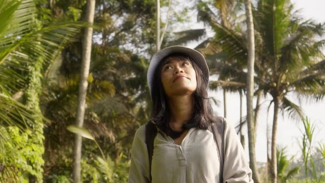 Asian female tourist enjoying view of rural tropical jungle road in remote part of Bali, Indonesia. Tourism vacation destination activity slow motion