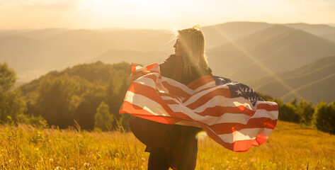 Woman holding USA flag on top of mountain and enjoys the view of the autumn rocks hills. Celebrating Independence Day of America.