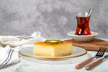 Revani dessert. Sweet semolina cake with pistachio. Ramadan sweets. Traditional Turkish cuisine delicacies. Revani dessert with syrup on a gray background.
