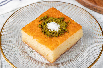 Revani dessert. Sweet semolina cake with pistachio. Ramadan sweets. Traditional Turkish cuisine delicacies. Revani dessert with syrup on a gray background. Close up