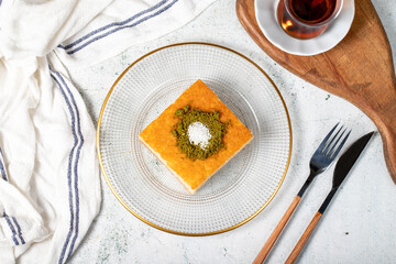 Revani dessert. Sweet semolina cake with pistachio. Ramadan sweets. Traditional Turkish cuisine delicacies. Revani dessert with syrup on a gray background. Top view
