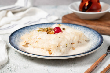 Gullac dessert with walnuts. Ramadan sweets. Traditional Turkish cuisine delicacies. Gullac dessert with cherry, pistachio and walnuts on gray background
