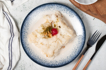 Gullac dessert with walnuts. Ramadan sweets. Traditional Turkish cuisine delicacies. Gullac dessert with cherry, pistachio and walnuts on gray background. Top view