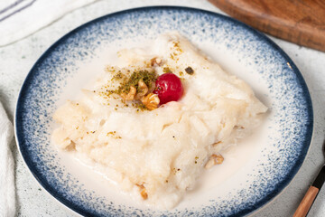 Gullac dessert with walnuts. Ramadan sweets. Traditional Turkish cuisine delicacies. Gullac dessert with cherry, pistachio and walnuts on gray background. Close up