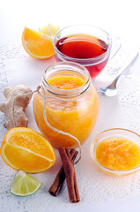 Orange jam in a jar. Tea and citrus fruits on a white table.