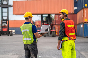Professional engineer container cargo foreman in helmets working standing and using walkie talkie checking stock into container for loading.logistic transport and business industry export