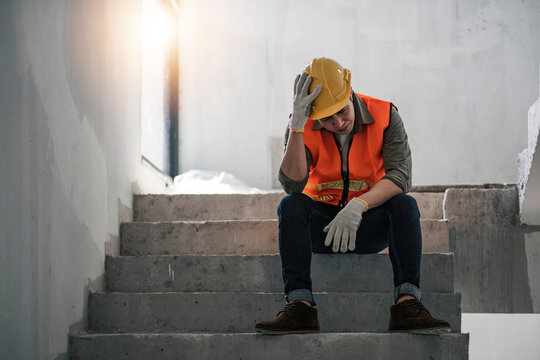 Stress engineer or architect holding hands at his head. He is having problems in work. He is sitting on stairs. Engineering concept.