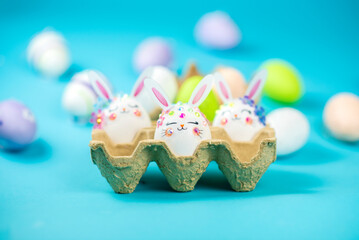 funny easter eggs with a face, muzzle of rabbits on a blue background	