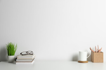 Comfortable workplace with white desk near wall. Space for text