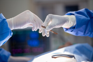 Team of surgery doctor in Operating Room hold hands scalpel surgical blade give to Surgeons During...