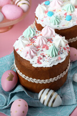 Traditional Easter cakes with meringues and painted eggs on pink background